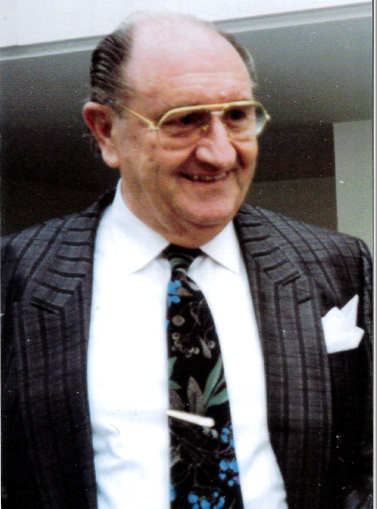 Harry Rytina im Nadelstreifenanzug mit gemusterter Krawatte und Einstecktuch, mit Brille.