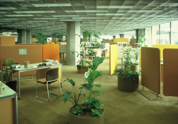 70er Büro-Design Innenraum eines gut beleuchteten Büros mit Schreibtischen, Trennwänden und Topfpflanzen.